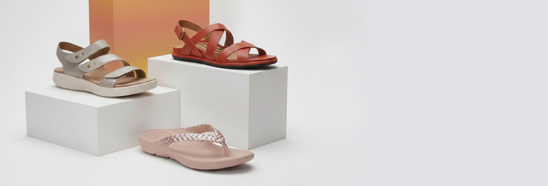 Three pairs of sandals on white boxes against a light background