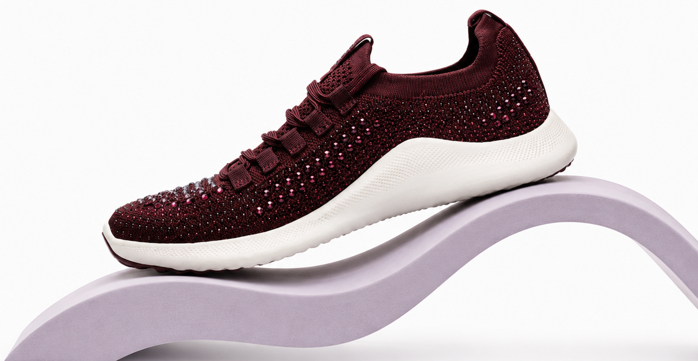 Maroon sneaker with white sole on a purple stand against a white background
