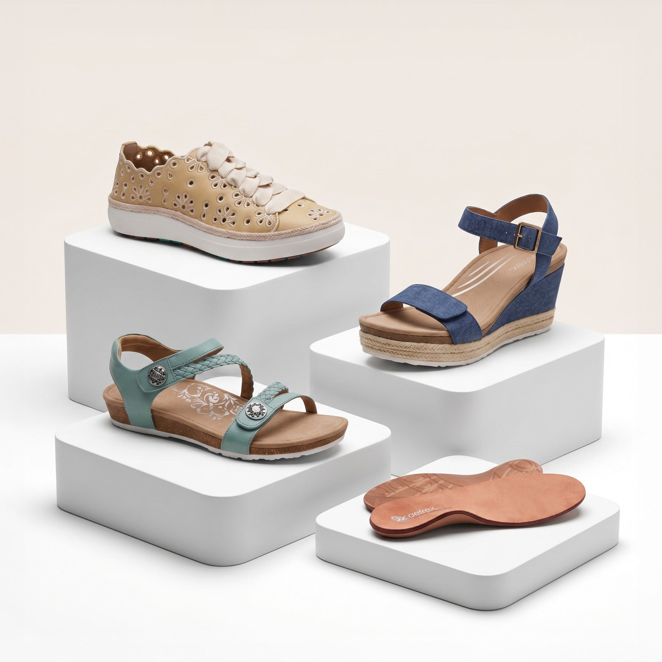 Four pairs of shoes on white stands against a light beige background