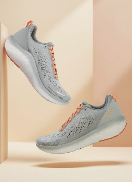 Gray running shoes with orange accents on a peach background