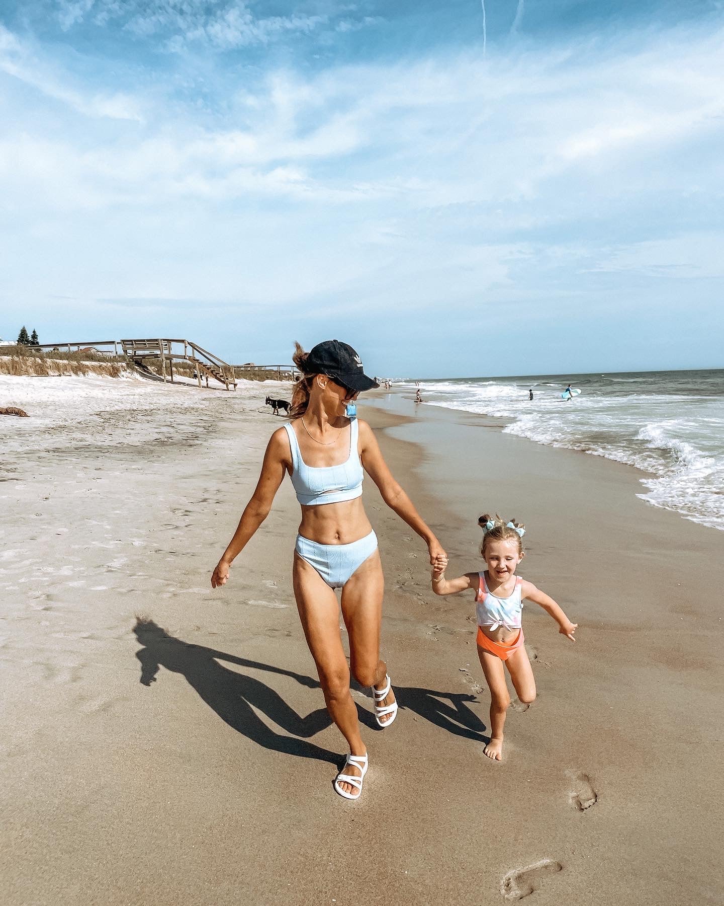Woman and child running on a beach with ocean and sky in the background