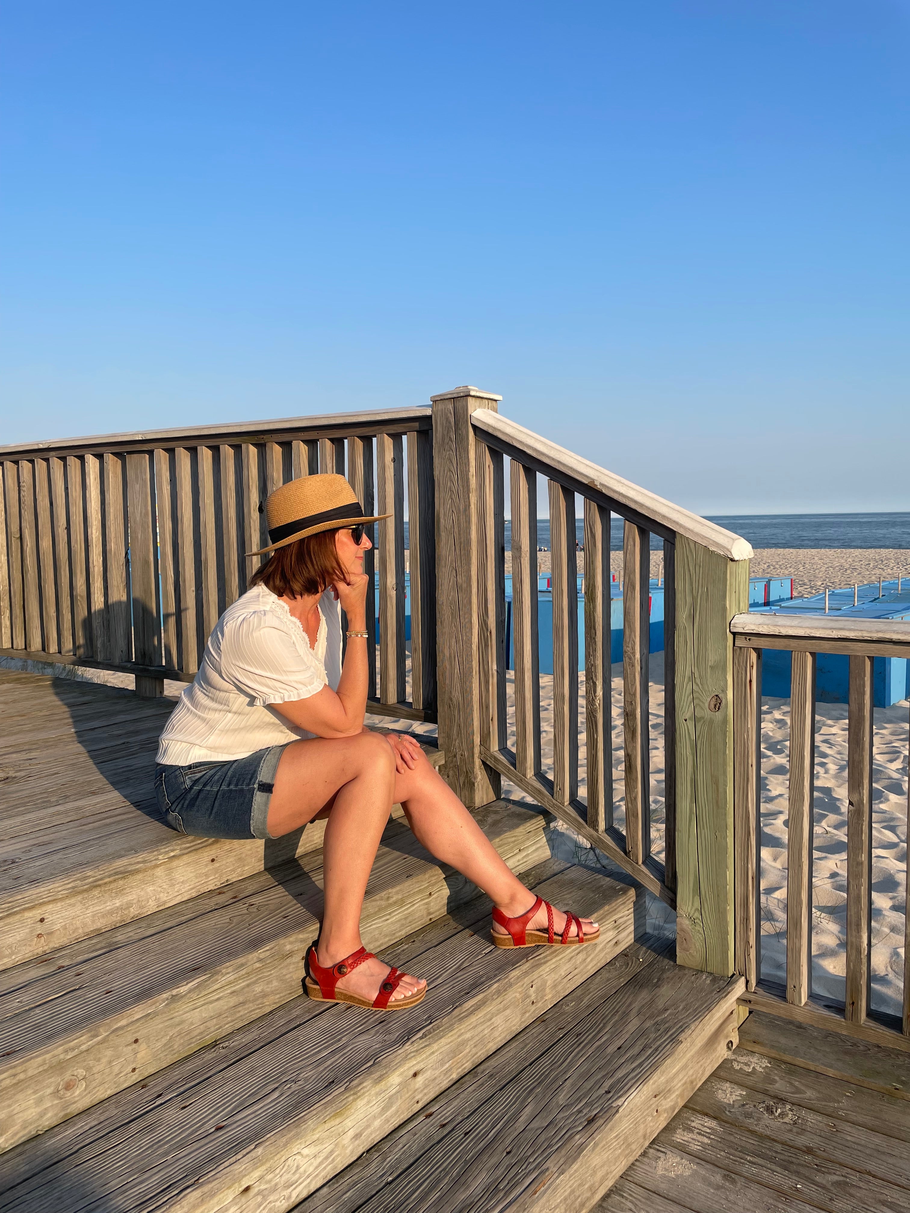 Woman sitting on a wooden staircase with a blue sky background