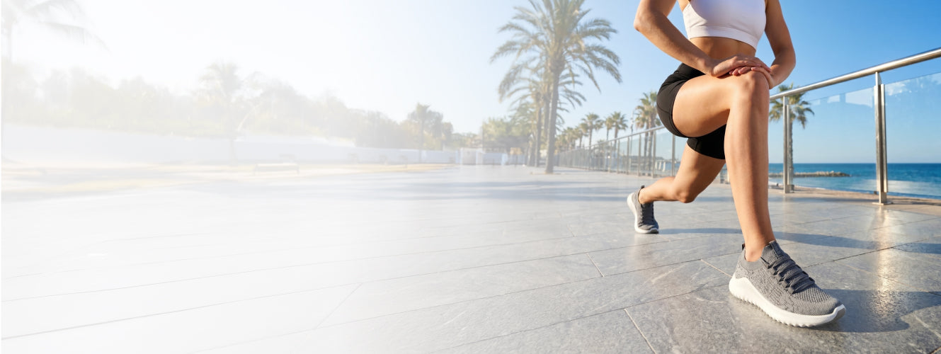 Person stretching on a promenade with palm trees and ocean in the background