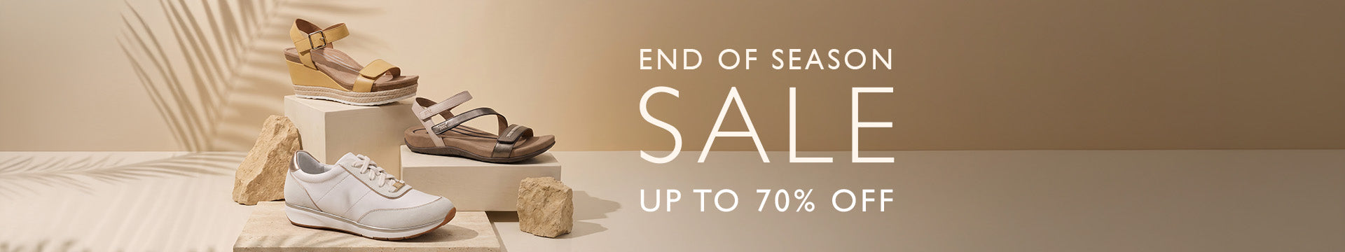 A promotional sale banner for a footwear collection, featuring a white sneaker, brown sandals, and gold heels displayed on pedestals with wooden blocks against a warm beige background with text reading 'END OF SEASON SALE UP TO 70% OFF'.