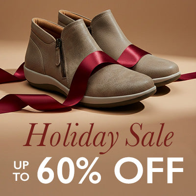 Pair of beige ankle boots with a red ribbon on a brown background, promoting a holiday sale with text 'Holiday Sale Up to 60% Off'.