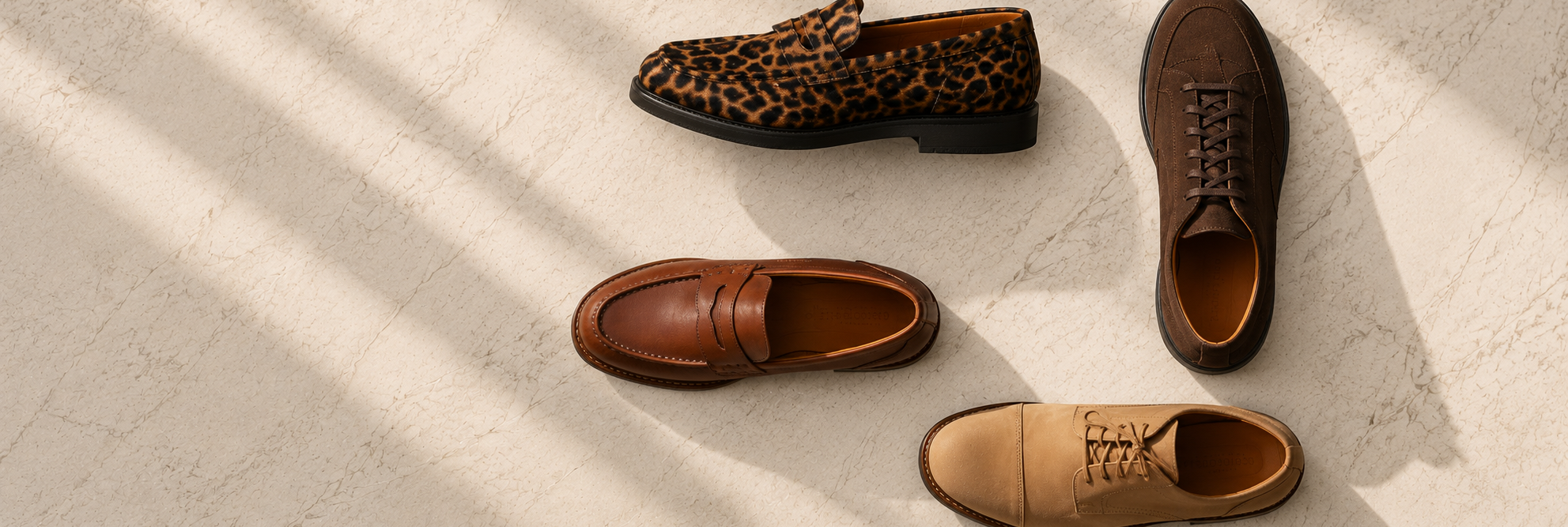 Four pairs of brown leather shoes on a light stone surface