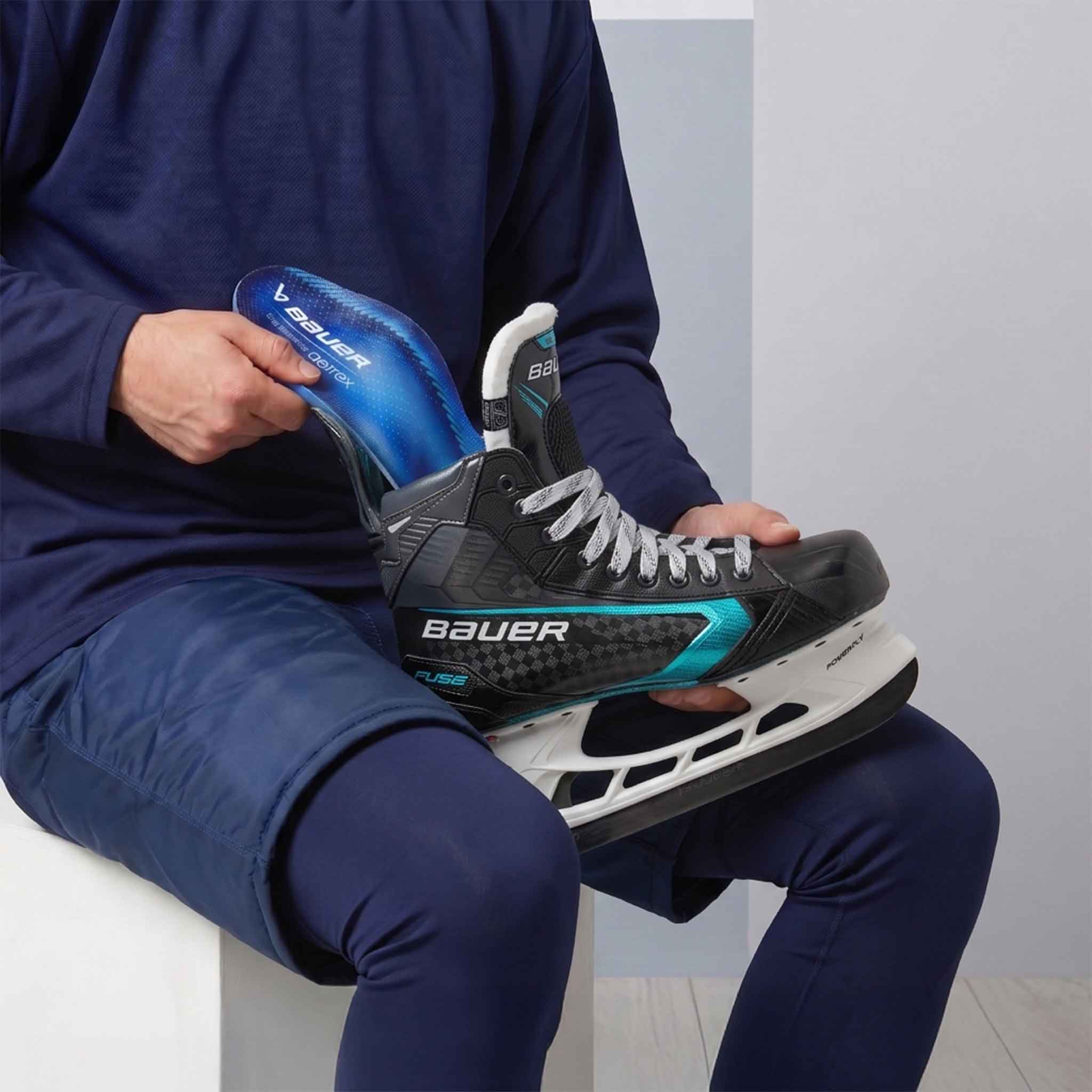 Person holding a black ice skate with blue orthotic